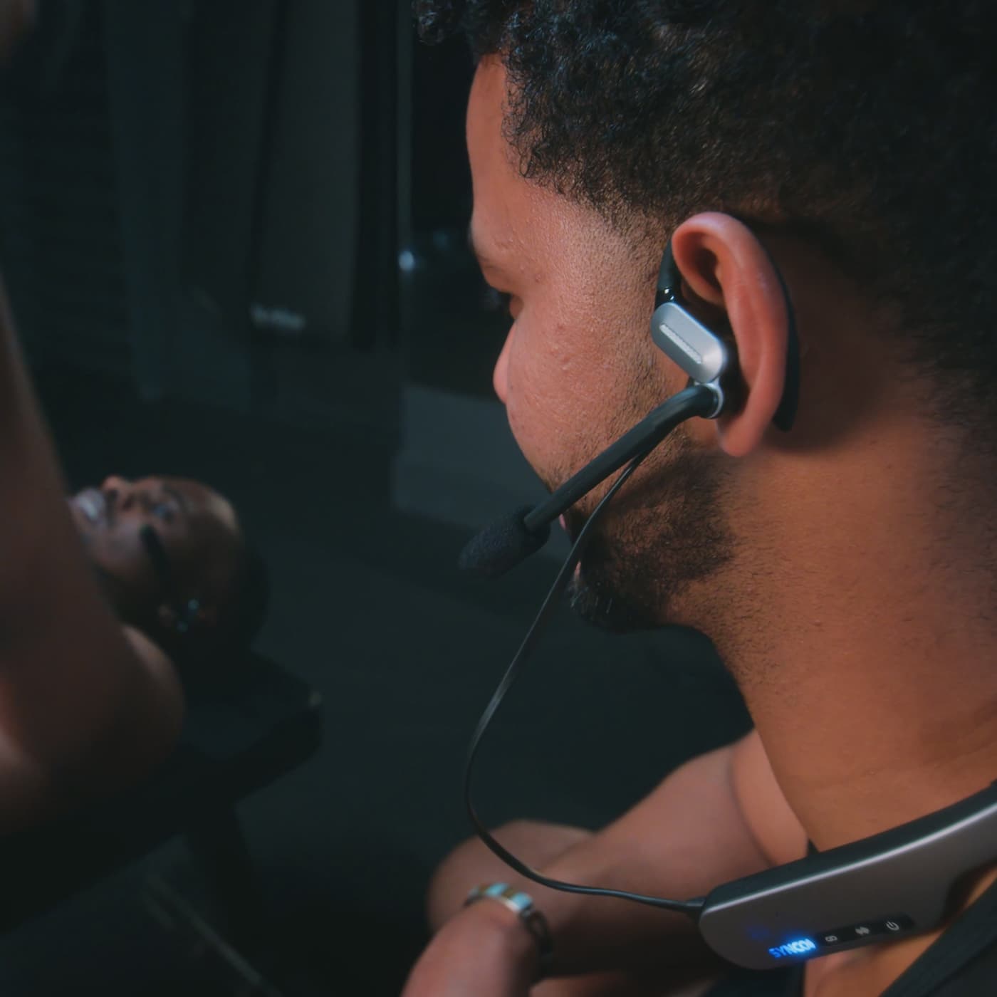 A fitness trainer uses the SYNCO Xtalk S in-ear intercom headset to coach a gym session.